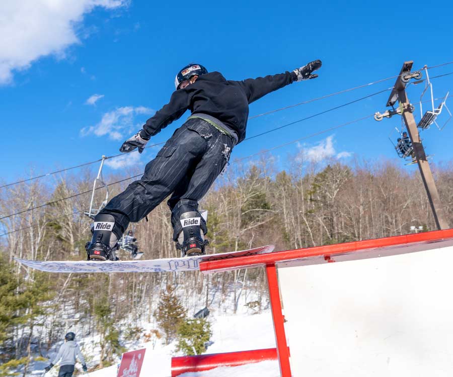 Snowboarder on "The 32" rail during Rail Jam in Stinger terrain park.