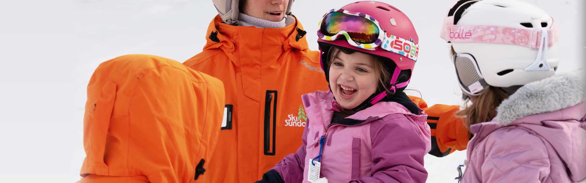 Two girls with their instructors having fun during ski lesson.
