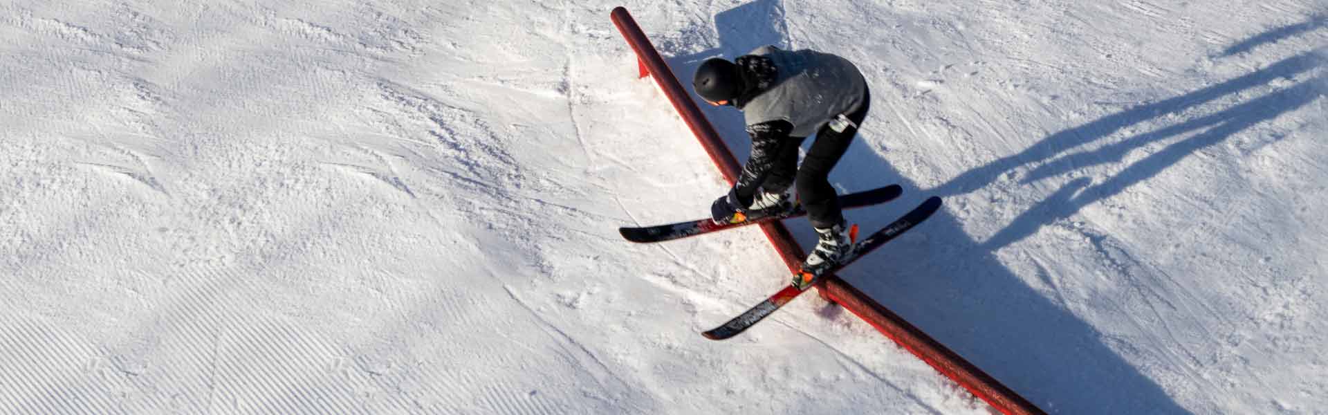Aerial view of skier on elbow rail feature in Stinger terrain park.
