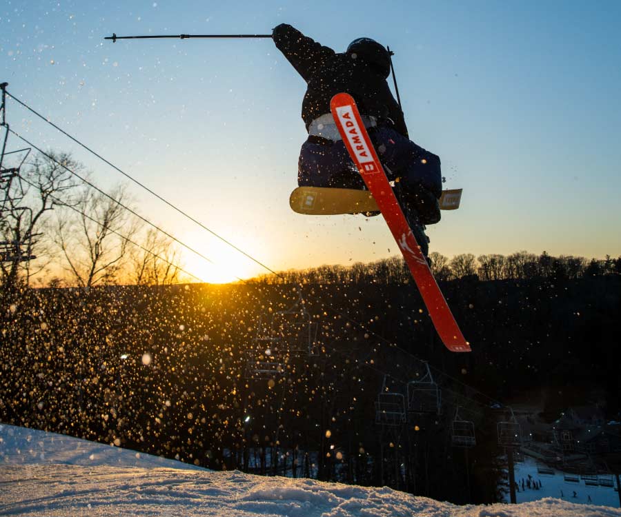 Skier going off jump with ski grab in Stinger terrain park.