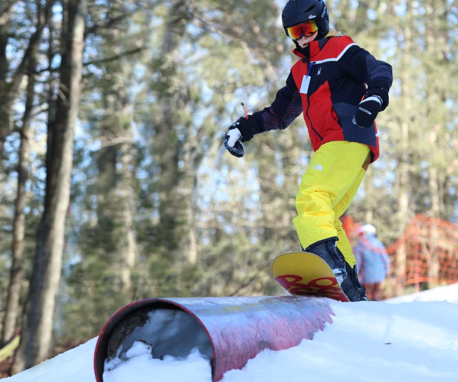 Snowboarder on "lift tower" rail in Stinger terrain park.